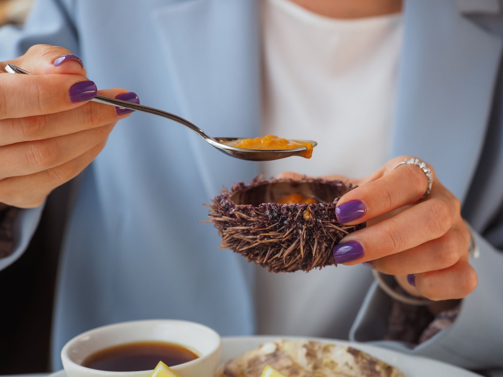 Close-up of a sea urchin being enjoyed with a spoon, highlighting gourmet dining.